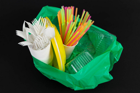 塑料废物危险生态学概念与全垃圾袋和五颜六色的单用吸管餐具杯板砂锅盒在黑色背景下隔离