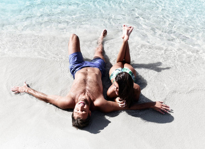 快乐愉快的情侣躺在沙滩海边玩得开心。浪漫假期, 蜜月之恋
