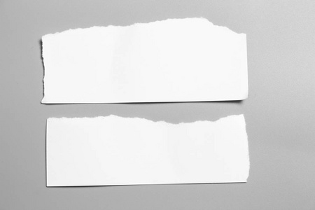 灰色背景上的白色撕裂纸。收纸 rip