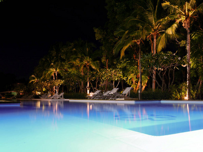 美丽的游泳池在夜视图与椅子在附近