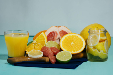 柑橘 橘子 柠檬 酸橙 葡萄柚，柚老式板 柠檬水和玻璃绿松石背景上一杯果汁