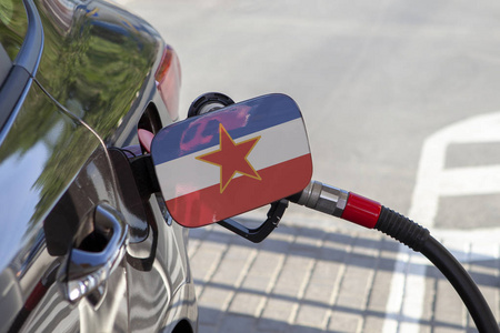汽车油箱填料襟翼上的 Yougoslavie 旗。加油站用汽油泵加油的汽车。加油站。汽油和石油产品。特写