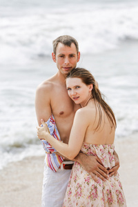 海滩背景下美丽情侣拥抱的肖像