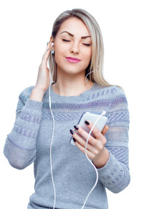 享受音乐使用头戴式耳机，孤立在白衣的年轻女子的画像
