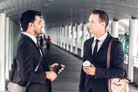 两个微笑的商人同事在黑色西装说话和工作. 论现代城市中的商务人士讨论策略