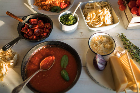 意大利面配辣番茄酱, 干酪和罗勒。盘子里配有美味的面食芝士锅里有有机番茄酱和厨房木板的木桌, 上面的景色。烹饪产品。软焦点