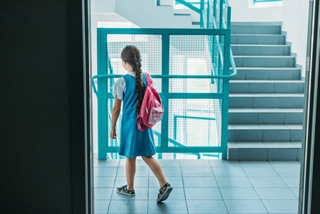 在学校走廊上穿着背包的小女生的后视图