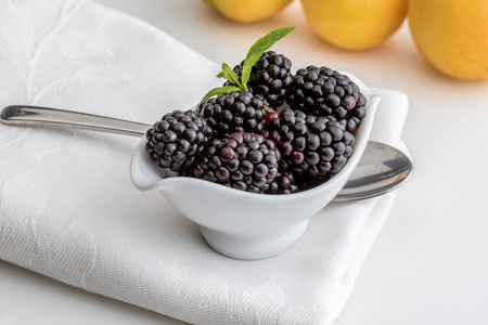美味的新鲜黑莓和成熟的黑色和红色石榴石。在白色碗和孤立的背景。与杏