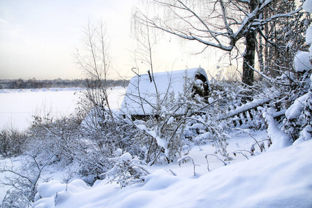 典型的俄罗斯遗弃白雪覆盖的村庄在冬季晚上和下雪周围的树木