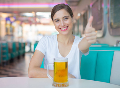 年轻漂亮的女人喝一品脱啤酒到美国餐厅