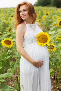 怀孕的女孩在用向日葵领域