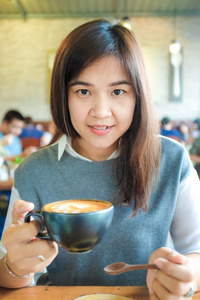 亚洲的年轻女子在艺术咖啡馆喝咖啡