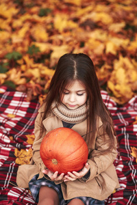南瓜小女孩坐在秋季公园