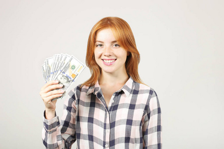 年轻漂亮的红发女人的肖像, 拿着一大把的钱持有100美元的栈像风扇。兴奋诱人的红头发女性 w大量现金。背景, 复制空间, 