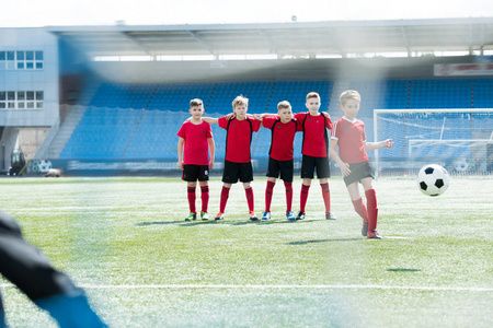 少年足球队男童全长肖像在练习中站在前排队长球在前台, 复制空间