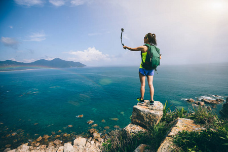 在海边徒步旅行的女子带着手机自拍