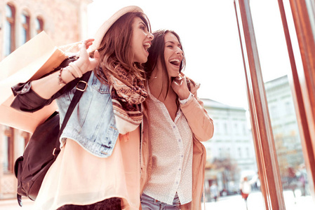 两个漂亮的微笑的女孩购物袋走在街上后, 好购物