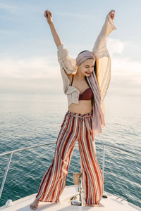 快乐时尚的女孩高兴与期待已久的假期, 举起她的手, 在游艇上