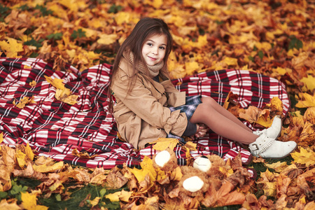 小女孩在公园秋叶玩耍