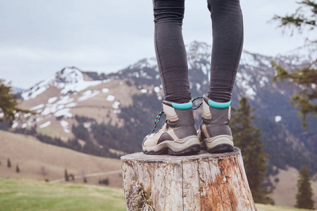 女性经典真皮登山靴的特写在山上的树桩上穿的妇女旅行和户外活动概念