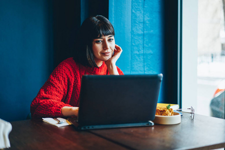 无忧无虑的时髦女孩享受在线购物通过笔记本电脑在自助餐厅午餐, 成功的妇女观看积极的网络研讨会的动机使用上网本和良好的 wifi 