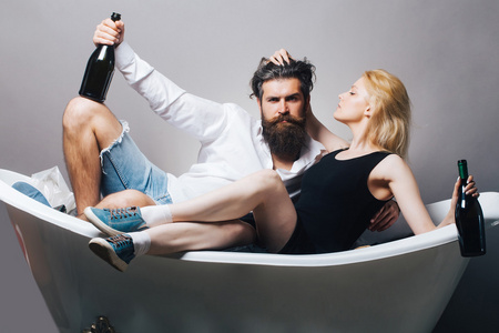 年轻的夫妇在浴缸与葡萄酒瓶