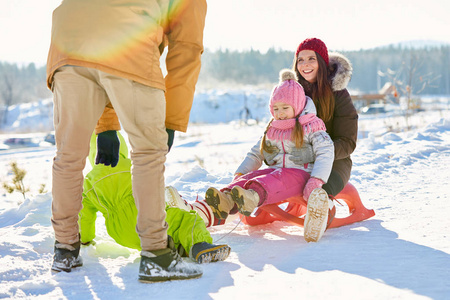 欢快的白种家庭与小孩子雪橇在乡下美丽的冬季下午