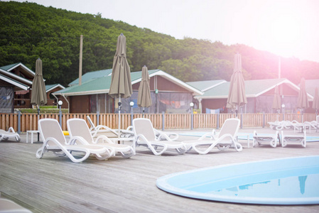 乡村俱乐部休闲娱乐休闲泳池木屋森林树太阳躺椅伞。美丽的自然景观