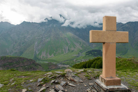 十字架上的石头金字塔上 Kazbek 登上背景附近 Gergeti 三位一体教堂