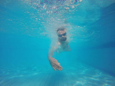 戴着眼镜在池中的水游泳的胡子男人