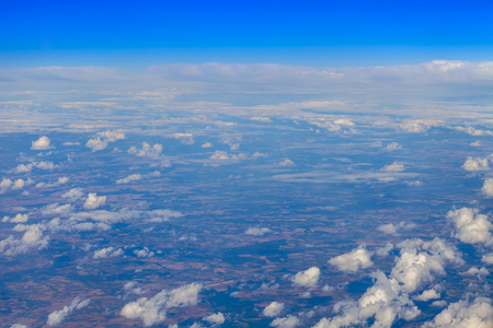 天堂般的景观。视图的白云和陆地表面点燃，阳光从窗口正在飞行的飞机