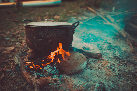 野营和烹饪在野外条件下, 在篝火上煮沸的锅在早晨野餐。当你去野外或户外活动时, 用木柴在柴火炉上做饭, 露营帐篷