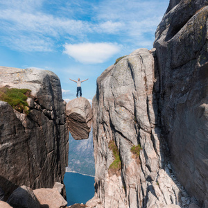 一个极端计划的肖像旅行为英俊的老人在 kjerag 的石头上的 kjeragbolten 挪威, 自拍在你的自由手中手持智能手机