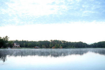 美丽的风景与森林和房子在湖附近。野营季节
