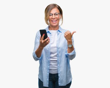 中年妇女短信发送信息使用智能手机在孤立的背景下指向和显示与拇指到一边, 快乐的脸微笑