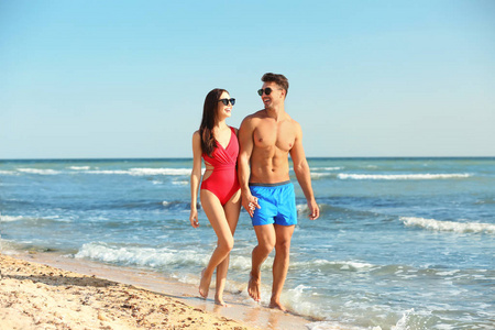 快乐的年轻夫妇一起漫步在海滩上