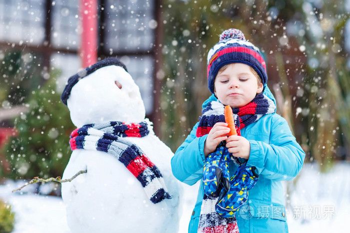 有趣的孩子男孩在冬天的户外堆雪人