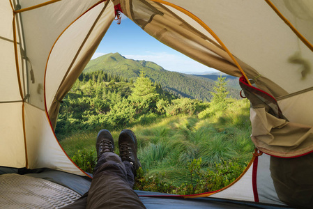 在山上露营。夏天远足。从山顶上的旅游帐篷观看。登山靴的家伙
