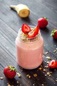 草莓和香蕉奶昔配自制燕麦。健康的早餐或小吃。玻璃罐子里的香蕉和草莓奶昔