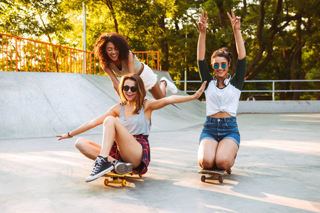 三激动的年轻女孩与滑板一起乐趣在公园