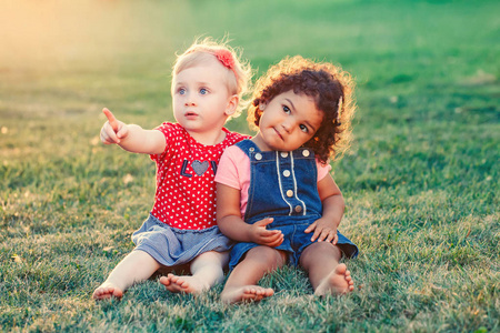 组肖像两个可爱可爱的女孩, 孩子们坐在一起。白人白种人和拉丁裔西班牙婴儿在公园外拥抱。友谊和最好的朋友永远的概念