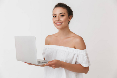 一个微笑的年轻的休闲黑发妇女的肖像手持笔记本电脑在白色背景下隔离