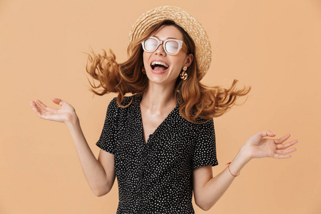 快乐可爱的女人的肖像20s 戴着草帽和太阳镜笑着与颤抖的头发隔离在米色背景