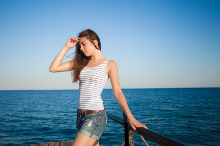 女孩站在码头上。美丽的大海背景