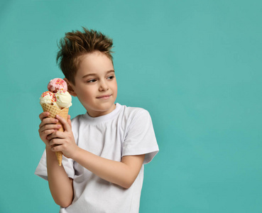 孩子抱着草莓香草冰淇淋在华夫饼锥快乐的微笑看着蓝色薄荷背景的角落