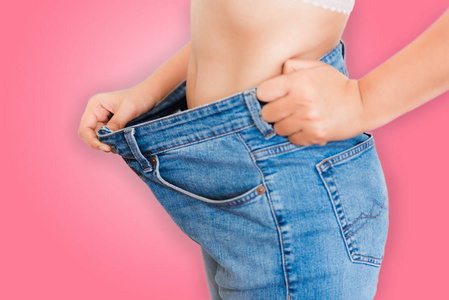 饮食概念, 特写的年轻女子显示成功的体重下降与她的牛仔裤隔离背景