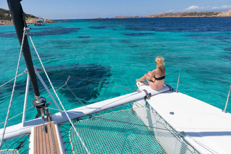 在夏季帆船巡游的女子放松, 坐在豪华的双体船在图片完美的绿松石蓝色泻湖附近 Spargi 岛在马达莱纳群岛, 撒丁岛, 意大利