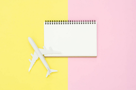 平面布局设计的旅游夏日概念顶部景观样机的空白白皮书笔记本和清晰的白色飞机上粉红色和黄色的粉彩彩色屏幕。夏天旅行在柔和的颜色背景
