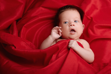 漂亮的宝宝躺在红色丝绸背景
