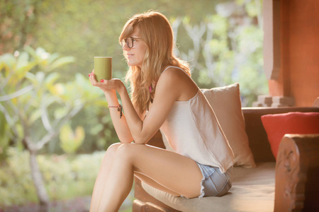 女孩喝咖啡茶和享受日出日落在花园里